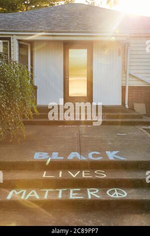 Portland, Oregon, USA - 2 giugno 2020: Il detto 'Black Lives Matter' scritto in gesso di fronte a una casa con il sole che si difende da dietro l'ho Foto Stock