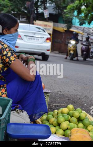 Hyderabad, Telangana, India. luglio-20-2020: Donna, commerciante di frutta stava indossando la maschera nel suo lavoro, donne che vendono i frutti sul lato della strada, piccola impresa Foto Stock