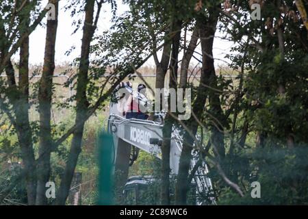 Harefield, Regno Unito. 22 luglio 2020. Un attivista della HS2 Rebellion occupa macchinari pesanti per ritardare la abbattimento degli alberi per HS2 lungo Harvil Road. Diversi attivisti ambientali hanno occupato macchinari e alberi in protesta contro il collegamento ferroviario ad alta velocità, che attualmente è previsto costare £106 miliardi e rimarrà un contributo netto alle emissioni di CO2 durante la sua durata prevista di 120 anni. Credit: Mark Kerrison/Alamy Live News Foto Stock