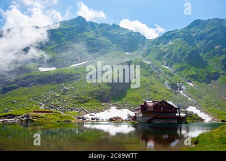 nuvole sopra il lago balea in romania. splendido paesaggio estivo nelle montagne fagaras. paesaggi che si riflettono in acque cristalline in una giornata di sole. Foto Stock