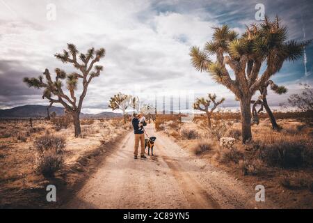 Un uomo con un bambino e un cane è in piedi In un deserto della California Foto Stock