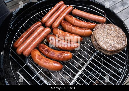 Hot dog e hamburger su un barbecue a carbone. Foto Stock
