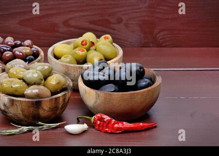 Olive intere nella ciotola di legno sul tavolo da vicino Foto Stock