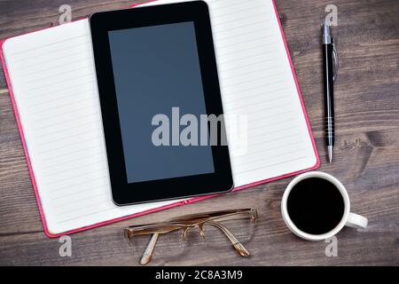 Primo piano di un tablet pc digitale con notebook, caffè e penna sulla scrivania Foto Stock