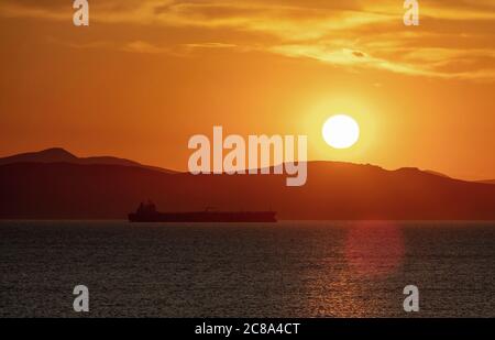 Tramonto arancione nuvoloso paesaggio sull'acqua di mare. Spettacolare e magico tramonto mare in Grecia mar Egeo. Crepuscolo, sfondo dell'alba. Terra e orang dell'isola oscura Foto Stock