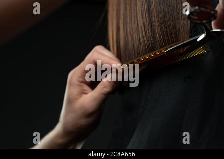 Ritaglio di capelli di parrucchiere facendo taglio a giovane donna in salone di bellezza Foto Stock