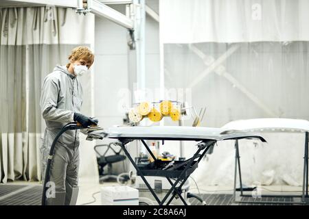 Meccanico automatico di grind auto parte per la verniciatura. Auto lavoro del corpo auto vernice di riparazione dopo incidente Foto Stock