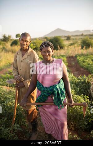 Una moglie e un marito stanno insieme tenendo le zanche nella loro fattoria nella contea di Makueni, Kenya, Africa. Foto Stock