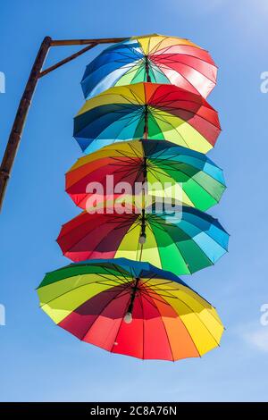 Luci di strada decorate con ombrelli colorati appendono su una colonna in strada contro il cielo blu in una giornata di sole, Vietnam Foto Stock