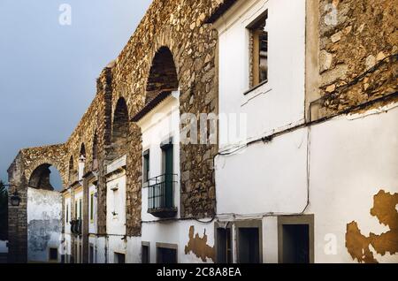 Case a Evora (Alentejo, Portogallo) lungo l'antico acquedotto di Agua da Prata. Gli edifici furono costruiti nel corso dei secoli direttamente tra gli archi di Th Foto Stock