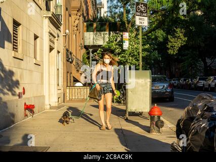 Donna che indossa la sua maschera cammina il suo cane il quartiere Chelsea a New York il Lunedi, 20 luglio 2020, il giorno New York entra nella fase 4 della riapertura. (© Richard B. Levine) Foto Stock