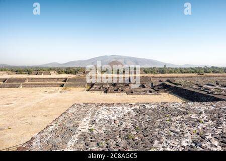 Tempio della Serpente Piumata di Teotihuacan Messico | TEOTIHUACAN, Messico — La Piramide del Sole si erge sopra le rovine delle piattaforme residenziali della Ciudadela, la sua massa incorniciata dal Cerro Gordo in lontananza. Con una base di 225 per 222 metri e un’altezza di circa 246 piedi (75 m), è la struttura più grande di Teotihuacan e una delle piramidi più grandi dell’America antica. Le piattaforme in primo piano un tempo facevano parte dei complessi residenziali densi che hanno conferito alla città la sua scala urbana. Foto Stock