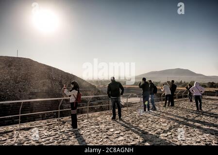 Tempio del Serpente Piumato Teotihuacan Messico | TEOTIHUACAN, Messico — I visitatori fotografano la valle circostante da una piattaforma panoramica vicino al Tempio del Serpente Piumato, illuminata dal sole del mattino sulle colline a est del Bacino del Messico. Il punto di vista si affaccia sulla Ciudadela, la piazza murata che un tempo circondava il tempio e che, secondo alcune stime, copriva circa 15 ettari. Il nucleo cerimoniale di Teotihuacan rappresentava solo una frazione di una città che si estendeva su circa 20-36 chilometri quadrati (8-14 miglia quadrate) al suo apice. Foto Stock