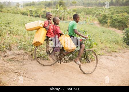 I bambini usano una bicicletta per prendere e trasportare acqua in un villaggio rurale nel distretto di Rakai, Uganda, Africa orientale. Foto Stock