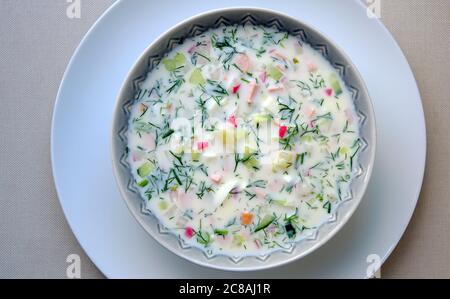 Okroshka. Zuppa di verdure fredde in un recipiente, fatta di cetrioli, potatoe, rossastro, prosciutto, uovo e aneto. A base di panna acida. Foto Stock