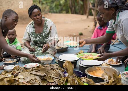 Una famiglia è seduta fuori casa per condividere un pasto insieme nel distretto di Kyotera, Uganda, Africa orientale. Foto Stock