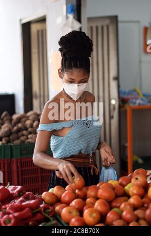 Giovane donna latina nera che acquista verdure in maschera facciale Foto Stock