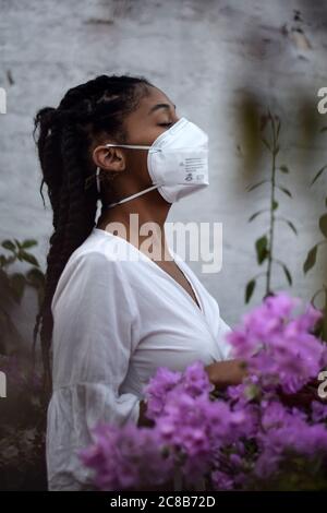 Giovane donna nera in maschera sul balcone Foto Stock