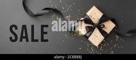 BLACK FRIDAY SALE Craft confezione regalo su sfondo scuro, decorata con un arco testurizzato a creare una romantica atmosfera di lusso. Per la vendita stagionale di shopping Foto Stock