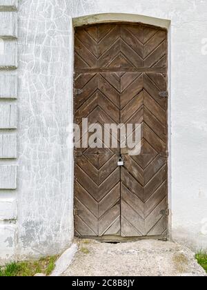 vecchia facciata dell'edificio con porta marrone di legno intemperie su pareti intonacate bianche Foto Stock