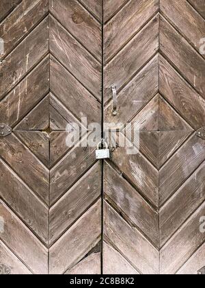 vista dettagliata di una vecchia porta in legno chiusa con lucchetto e tavole diagonali Foto Stock