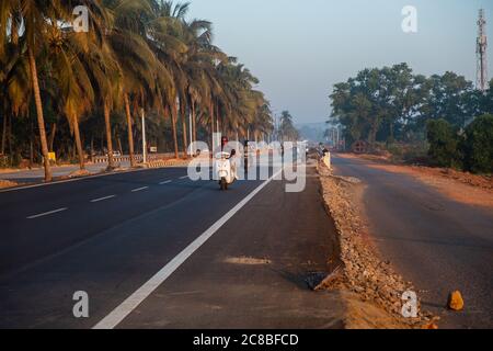 Morning Road tra alberi con motociclisti, Goa, India Foto Stock