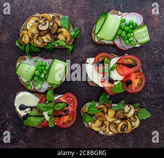 Aprire i toast vegetariani con diversi condimenti, vista dall'alto. Piatto di crostini di pane di segale Foto Stock