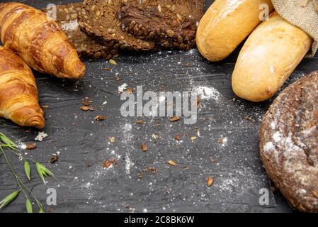 Cornice fatta di pane diverso e farina bianca su sfondo scuro di ardesia. Foto Stock