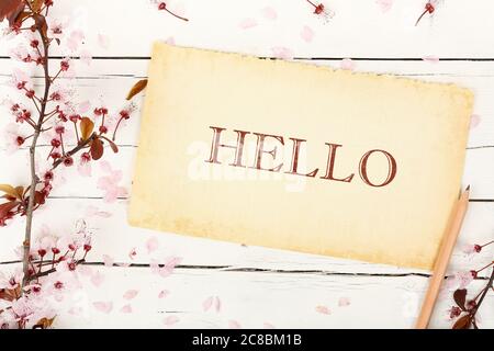 ciao scritto su carta invecchiata con ramoscello di mandorle su legno bianco Foto Stock
