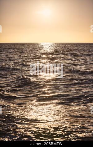 Tramonto sul mare riflesso in acqua, fuoco sulle onde nel mezzo della scena. Foto Stock