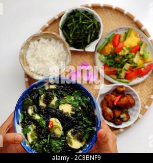 Cucina vietnamita vegana, pasto giornaliero per la famiglia a pranzo, cena, zuppa di alghe, tofu, verdure fritte, pane secco cuoco con salsa, spinaci in acqua bollita Foto Stock