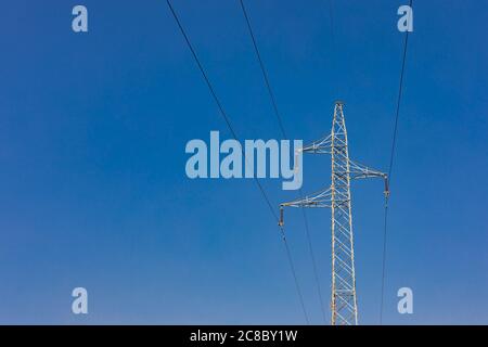 Potenza di trasmissione dell'elettricità. Torre ad alta tensione con fili su sfondo sfocato. Energia industriale Foto Stock