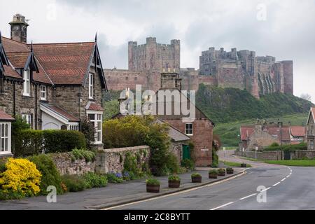 Church Street, Bamburgh, Northumberland, Inghilterra, Regno Unito, con il famoso castello oltre Foto Stock