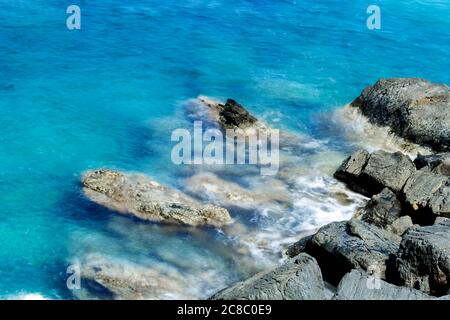 Lunga esposizione di surf sulla costa rocciosa dell'Elba dall'alto Foto Stock