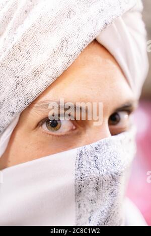 Foto verticale del volto di una donna caucasica vestita con un tradizionale abito berbero che ricopre il viso mentre si affaccia sulla fotocamera. Concetto di viaggio in Mo Foto Stock