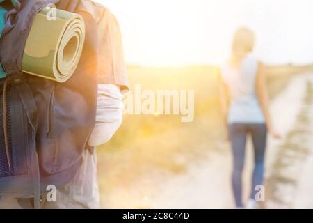 Zaino uomo da hiker con donna che cammina in primo piano sul campo Foto Stock