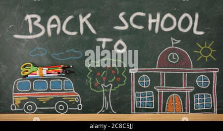 Creatività scolastica con autobus e scuola disegnati su lavagna con matite colorate e forniture scolastiche e messaggio di ritorno a scuola Foto Stock