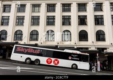 Il White Auckland Skybus ferma al terminal degli autobus di fronte a un edificio bianco. Nuova Zelanda Foto Stock