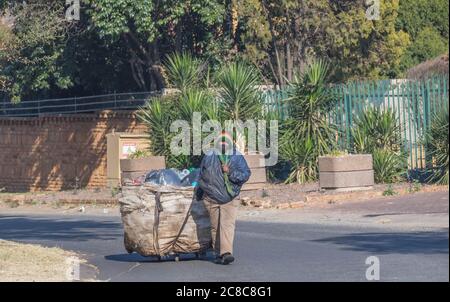 Alberton, Sudafrica - la donna nera non identificata raccoglie gli oggetti da riciclare per la rivendita dai rifiuti domestici in un quartiere residenziale Foto Stock