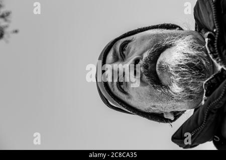 primo piano in bianco e nero, girato dal basso di un uomo di mezza età con barba, cappello e sguardo intenso Foto Stock