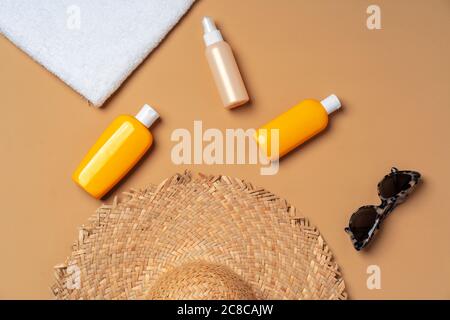 Prodotto cosmetico abbronzante con asciugamano, cappello e occhiali da sole Foto Stock