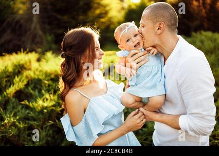 Famiglia felice amorevole fare divertimento con il bambino carino, i genitori giocare con il bambino, godere il fine settimana al parco Foto Stock