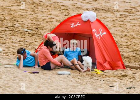 West Bay, Dorset, Regno Unito. 23 luglio 2020. Regno Unito Meteo. Una famiglia rilassante sulla spiaggia che è molto più tranquilla oggi presso la località balneare di West Bay in Dorset in una giornata nuvolosa con occasionali incantesimi di sole. Immagine: Graham Hunt/Alamy Live News Foto Stock