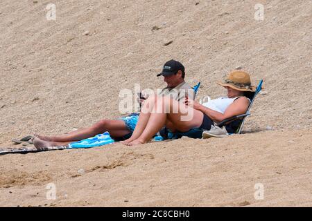 West Bay, Dorset, Regno Unito. 23 luglio 2020. Regno Unito Meteo. Una coppia di relax sulla spiaggia che è molto più tranquilla oggi presso la località balneare di West Bay in Dorset in una giornata nuvolosa con occasionali incantesimi di sole. Immagine: Graham Hunt/Alamy Live News Foto Stock