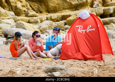 West Bay, Dorset, Regno Unito. 23 luglio 2020. Regno Unito Meteo. Una famiglia rilassante sulla spiaggia che è molto più tranquilla oggi presso la località balneare di West Bay in Dorset in una giornata nuvolosa con occasionali incantesimi di sole. Immagine: Graham Hunt/Alamy Live News Foto Stock