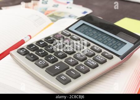 Le banconote e le monete in euro con la calcolatrice. Le banconote in euro e blocco note su sfondo di legno. Foto per tassa, il profitto e la determinazione dei costi. 50 euro, 20 euro, 10 euro. Mo Foto Stock