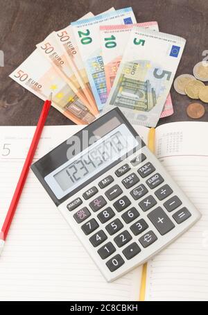 Le banconote e le monete in euro con la calcolatrice. Le banconote in euro e blocco note su sfondo di legno. Foto per tassa, il profitto e la determinazione dei costi. 50 euro, 20 euro, 10 euro. Mo Foto Stock