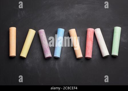 gesso multicolore su giace su tavola vuota nera in gesso, vista dall'alto Foto Stock