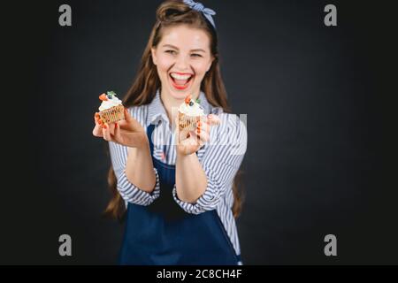 Felice giovane donna panetteria che tiene le cupcake in mano, offrendo al gusto Foto Stock