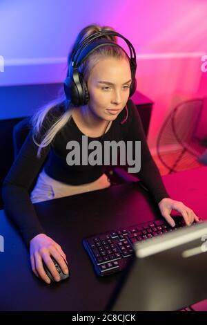 E-sport professionale focalizzato Gamer Girl con cuffia giocando Online Video Game su PC Foto Stock